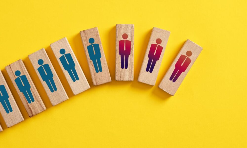 Wooden blocks that have worker graphics on them. Some are blue and and some are red to indicated laid off employees.